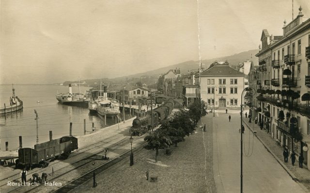 Einlaufender Dampfzug am Hafenplatz mit Hotel Anker