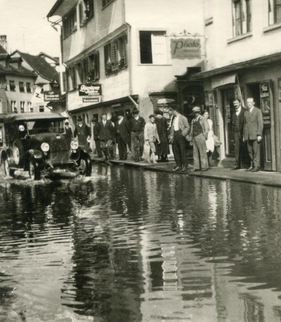 Hochwasserszene mit Automobil und Schaulustigen