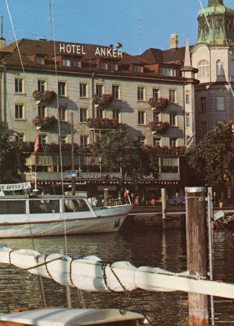 Nahaufnahme vom Hotel Anker und Hafenbecken mit Ausflugsboot