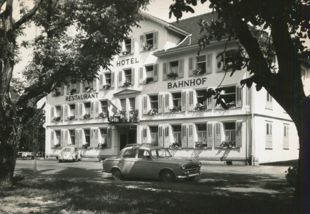 Hotel-Restaurant Bahnhof im aufgestockten Zustand mit Peugeot 403 und VW Käfer
