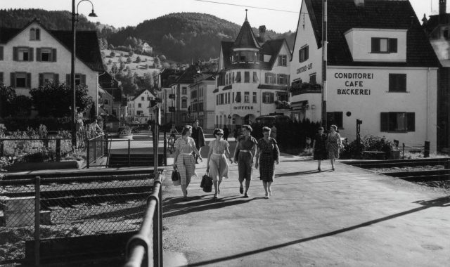 Belebte Strassenszene beim Bahnübergang mit Passantinnen